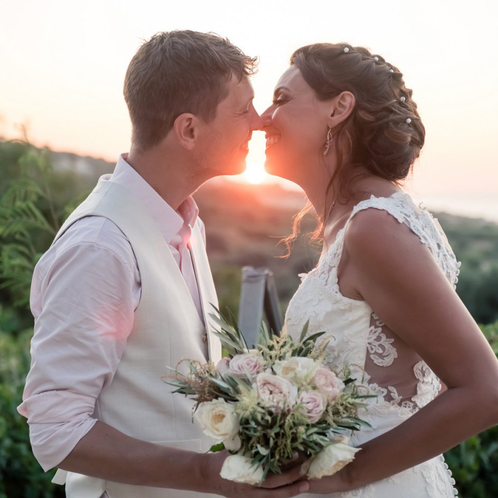 Couple de mariés échangeant un moment complice au coucher du soleil après leur cérémonie laïque.