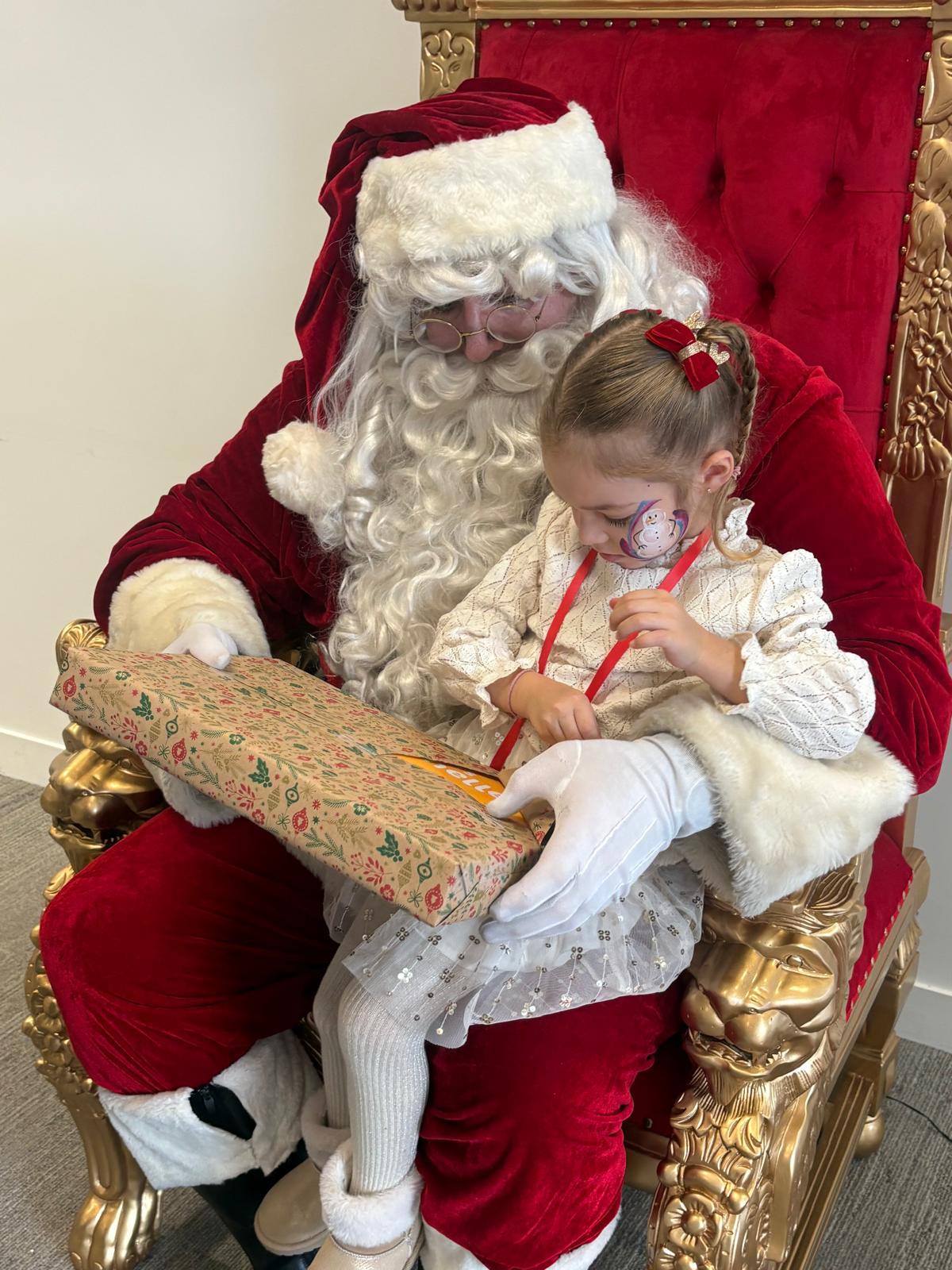 Enfant assise sur les genoux du Père Noël pendant l’arbre de Noël d’Olympus France