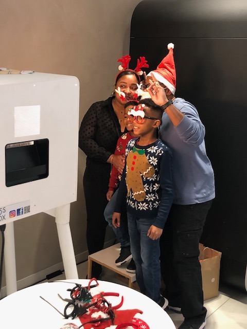 Famille posant avec des accessoires devant un photobooth de Noël