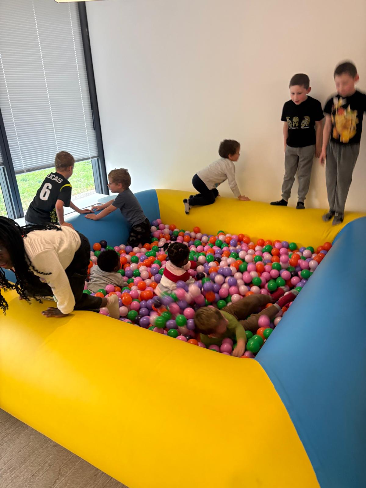 Enfants jouant dans une structure gonflable remplie de balles colorées