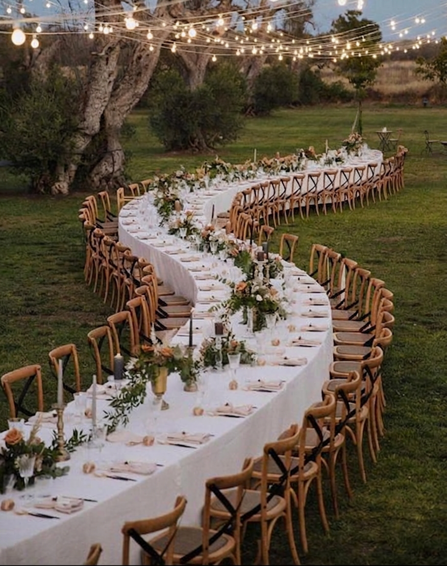 Longue table de réception disposée en vague dans un jardin