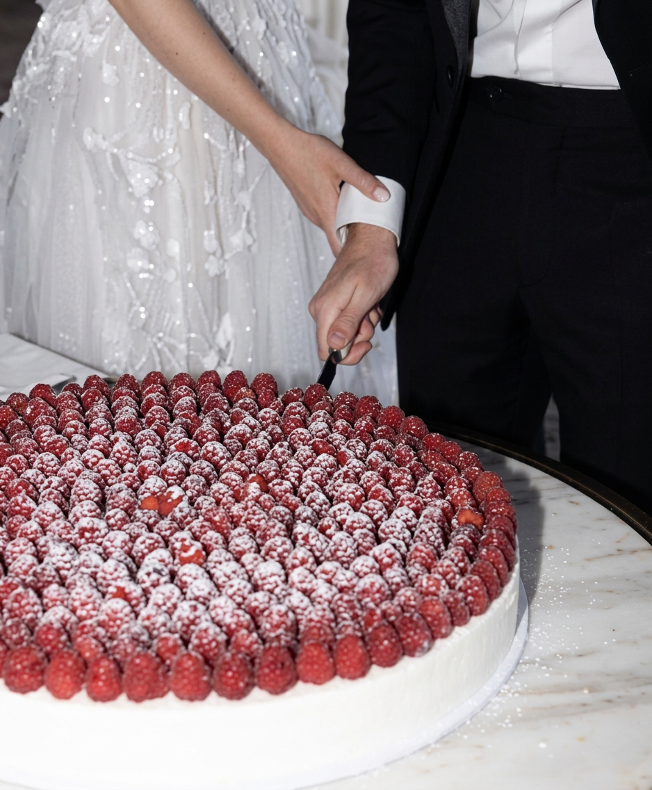 Mariés découpant un grand wedding cake à l’italienne garni de framboises